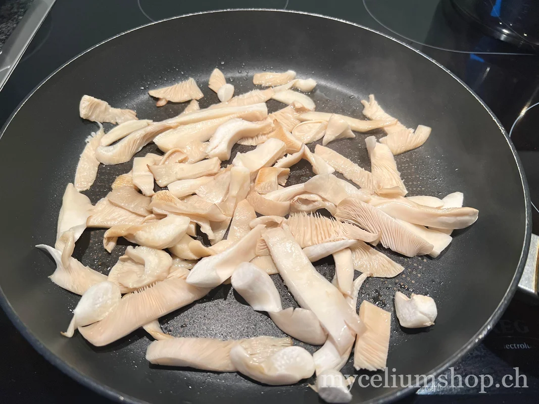 Pleurotes blancs coupés en lamelles régulières dans une poêle chaude