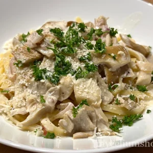 Gros plan sur des tagliatelles crémeuses aux lamelles de pleurote blanc, persil frais et parmesan râpé